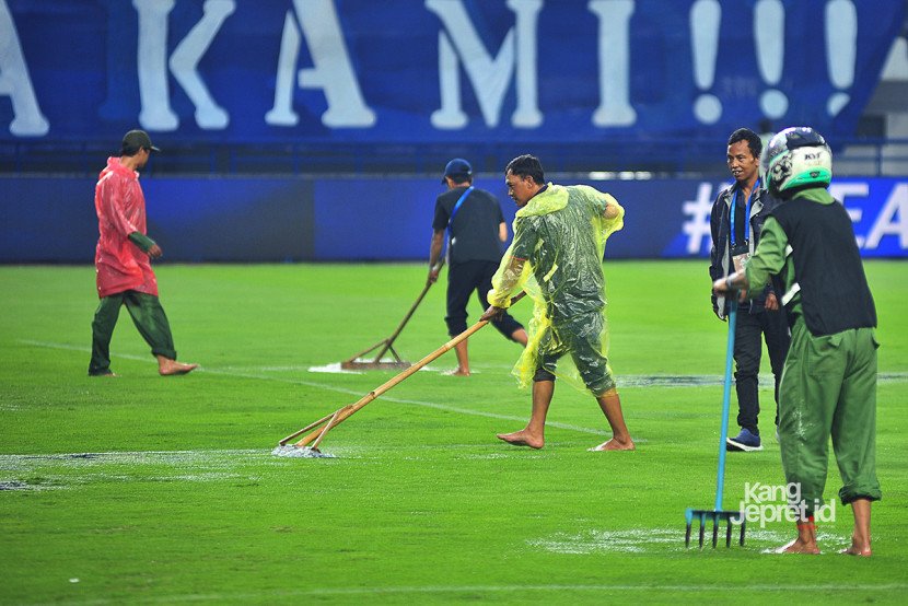 Petugas lapangan membuang air yang menggenangi lapangan stadion ketika laga Persib vs Persebaya dihentikan akibat hujan deras yang melanda Stadion Gelora Bandung Lautan Api, Bandung, Jumat (12/9/2025). (KANGJEPRET/ YOGI ARDHI) (Data: Nikon D700, Nikkor MF 300/2.8 ED)