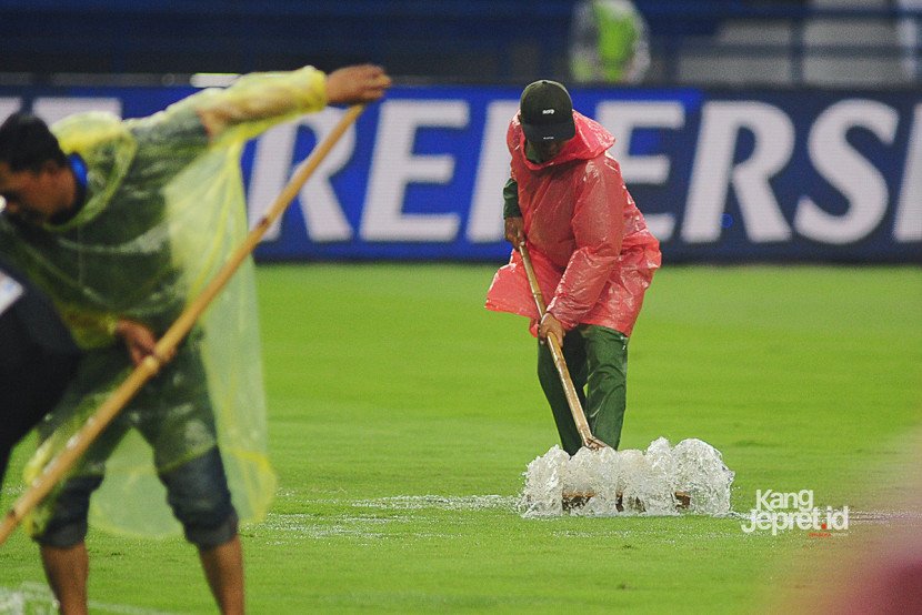 Petugas lapangan membuang air yang menggenangi lapangan stadion ketika laga Persib vs Persebaya dihentikan akibat hujan deras yang melanda Stadion Gelora Bandung Lautan Api, Bandung, Jumat (12/9/2025). (KANGJEPRET/ YOGI ARDHI) (Data: Nikon D700, Nikkor MF 300/2.8 ED)
