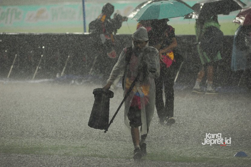 Seorang wartawan foto meninggalkan lapangan ssat hujan hujan deras yang melanda Stadion Gelora Bandung Lautan Api, Bandung, Jumat (12/9/2025). (KANGJEPRET/ YOGI ARDHI) (Data: Nikon D3, Nikkor AF 80-200/2.8 ED 3rd Gen)