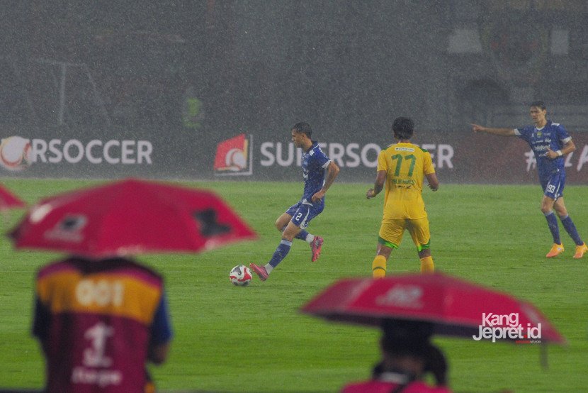 Wartawan Foto menggunakan payung pada laga Persib vs Persebaya yang berlangsung di tengah hujan deras ekstrem yang melanda Stadion Gelora Bandung Lautan Api, Bandung, Jumat (12/9/2025). (KANGJEPRET/ YOGI ARDHI) (Data: Nikon D700, Nikkor MF 300/2.8 ED)