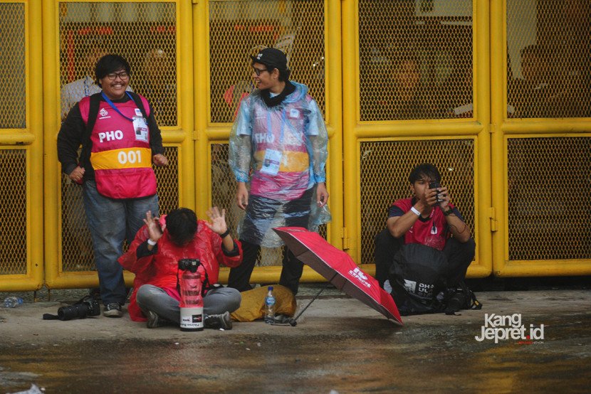 Beberapa orang wartawan foto berteduh dari hujan saat laga Persib vs Persebaya dihentikan akibat hujan deras yang melanda Stadion Gelora Bandung Lautan Api, Bandung, Jumat (12/9/2025). (KANGJEPRET/ YOGI ARDHI) (Data: Nikon D3, Nikkor 80-200/2.8 ED 3rd Gen)